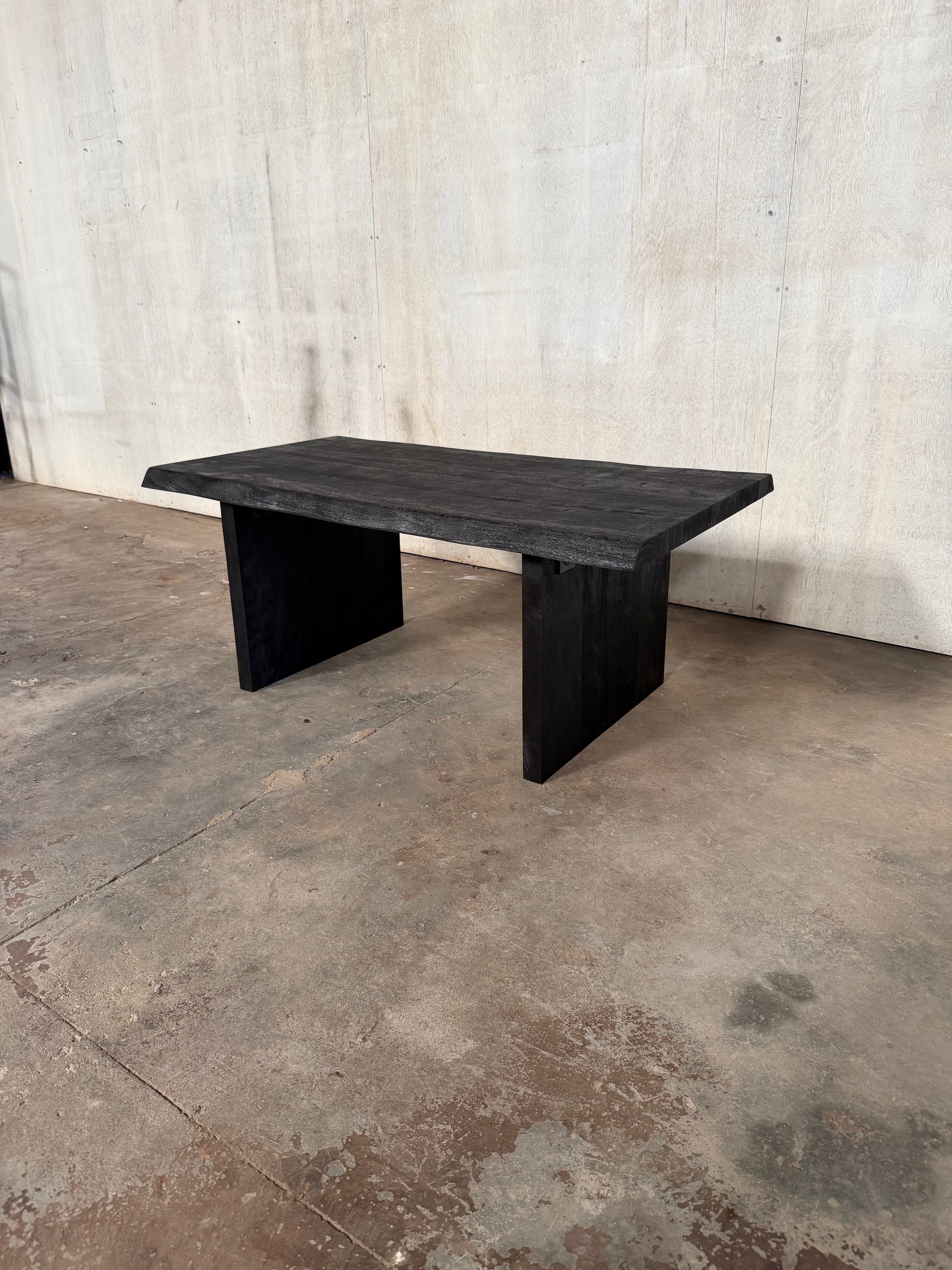 Black acacia table on a textured concrete wall.