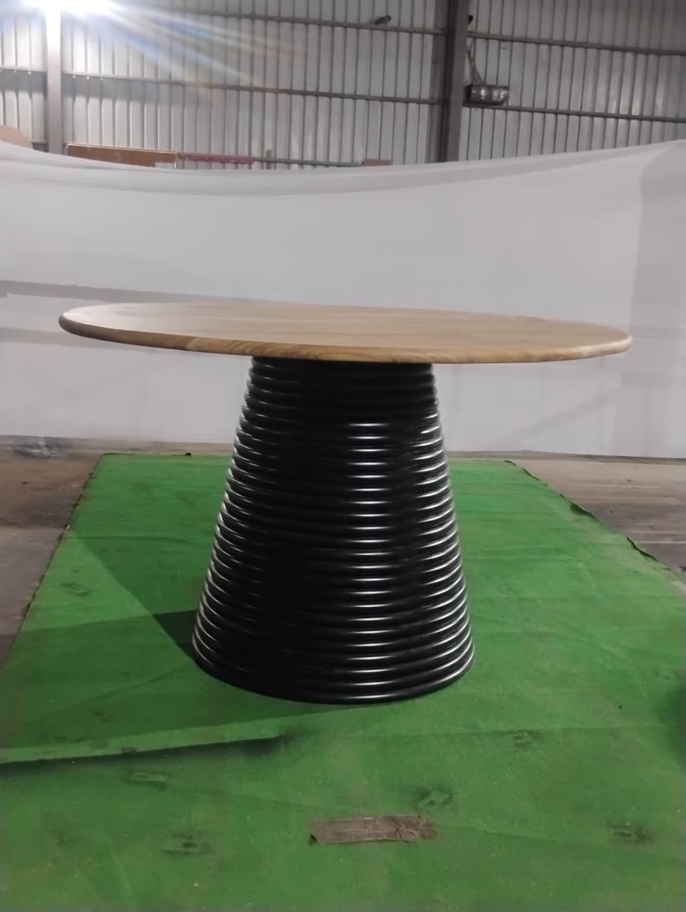Round wooden table with a black spiral base on a green mat