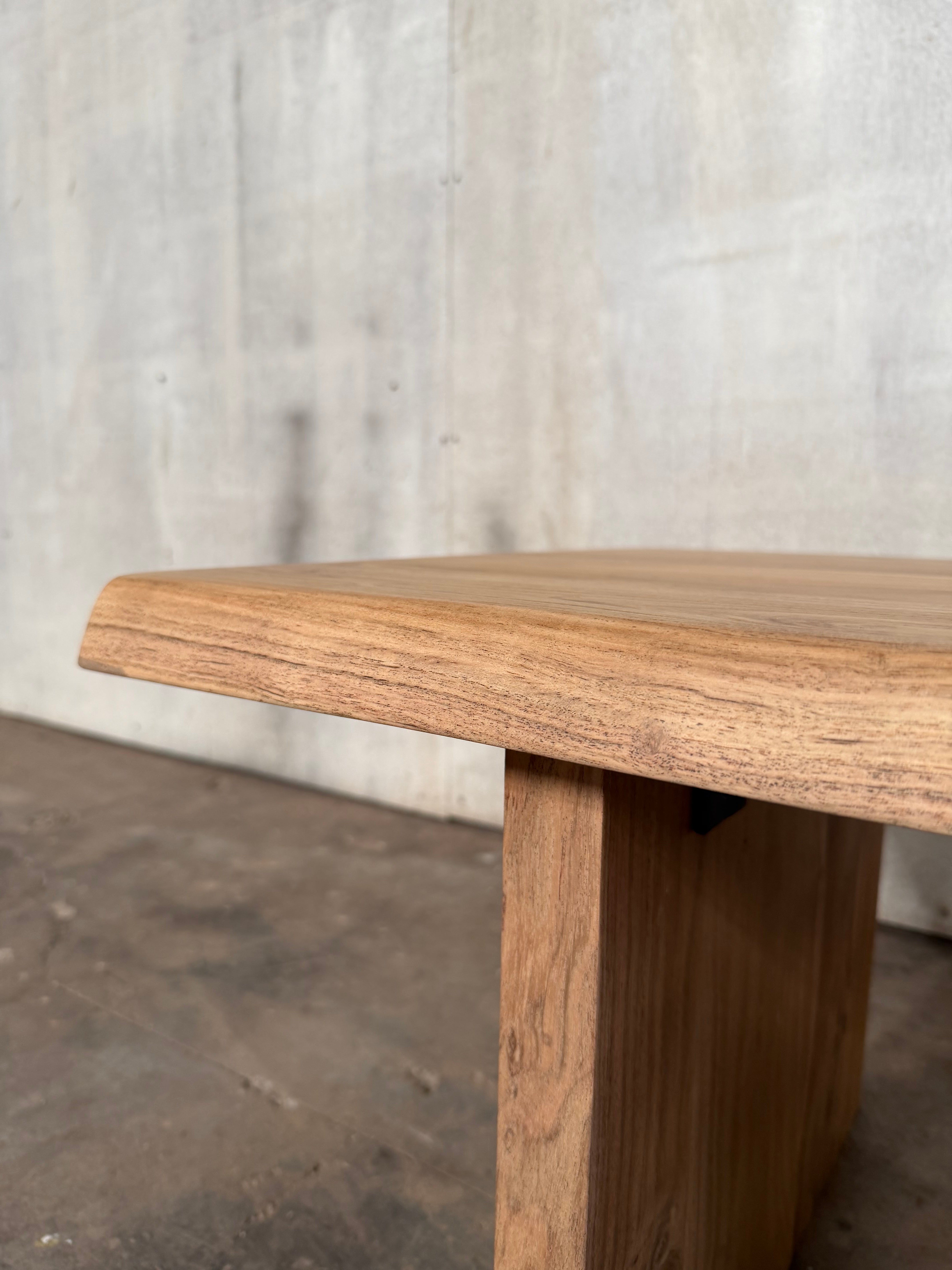 Close-up of a wooden table leg on a light gray floor.